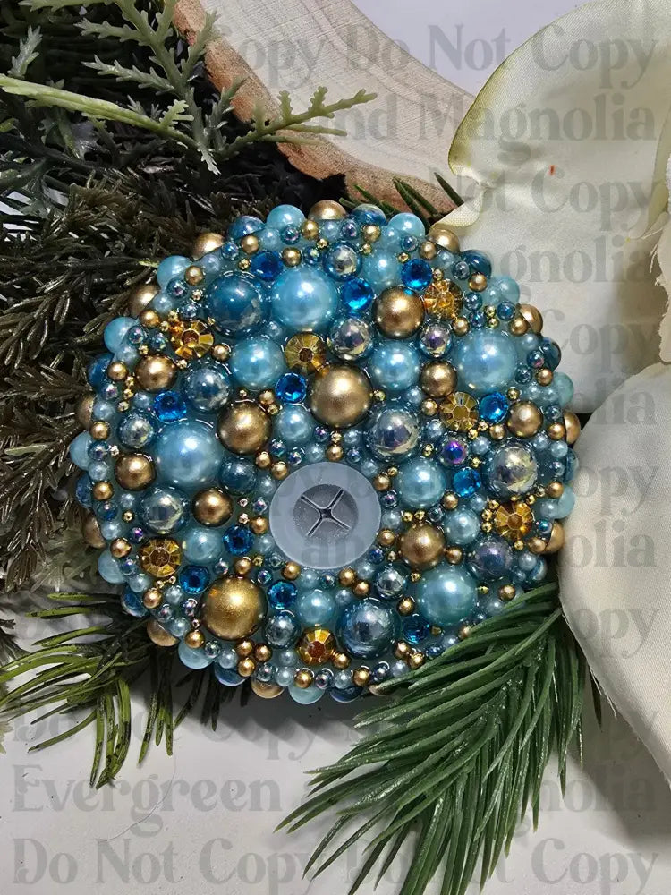 Decorative ornament with blue and gold beads on a floral and greenery background
