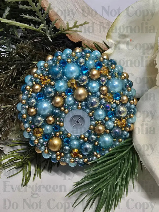 Decorative ornament with blue and gold beads on a floral and greenery background