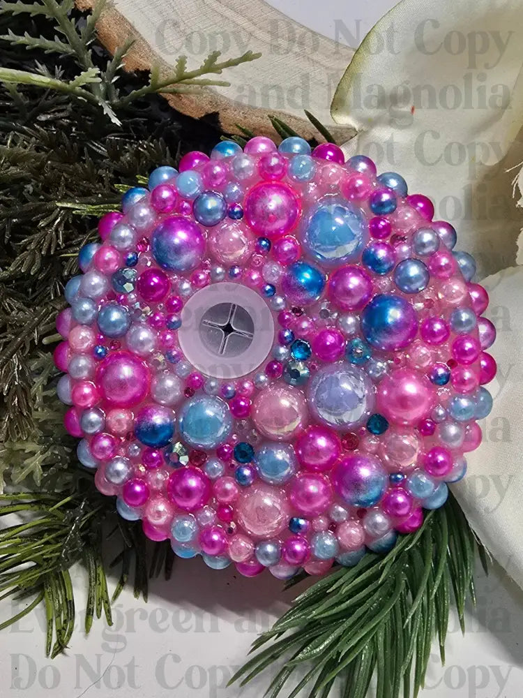 Decorative pink beaded ornament on a floral and greenery background